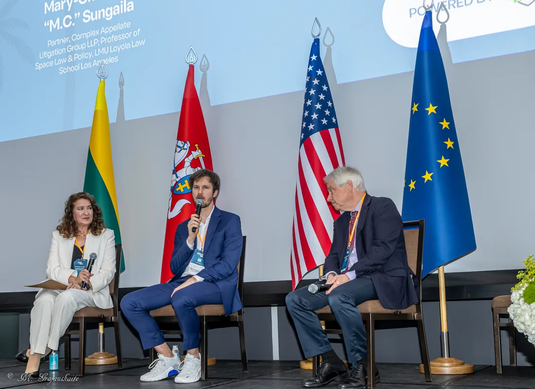 A panel discussion on stage in front of national flags