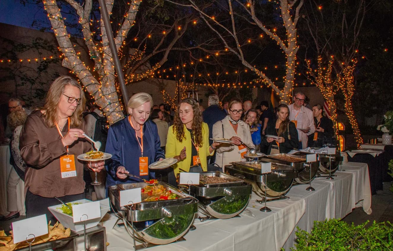 Guests serving food at an outdoor evening networking dinner