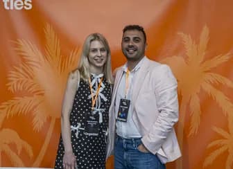 Two attendees posing together in front of a decorative backdrop